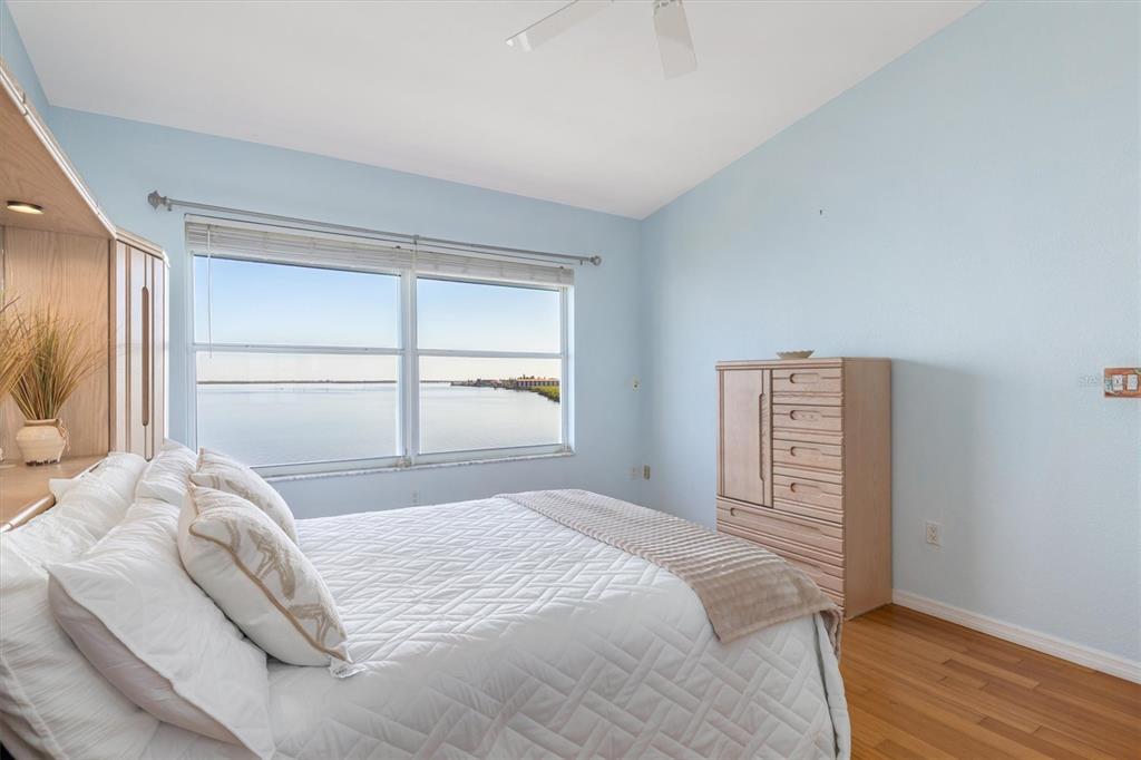 A bedroom with light blue walls, a bed, a wooden dresser, and a water view — 200 HARBOR WALK DRIVE UNIT 354, PUNTA GORDA, FL