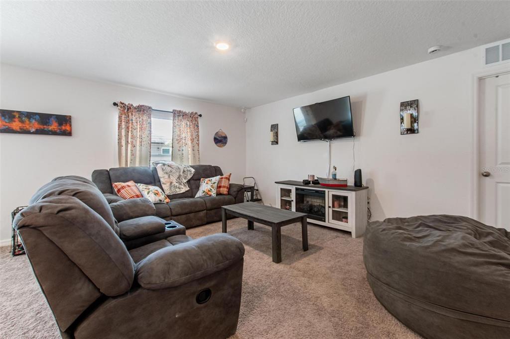A living room features gray carpet, a sectional sofa, a television, and a coffee table — 500 RIO GRANDE DRIVE, KISSIMMEE, FL