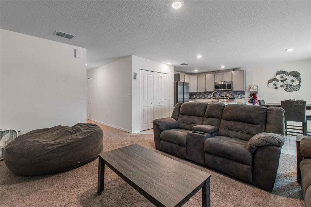 A living room with a gray sofa, beanbag chair, coffee table, and an open kitchen — 500 RIO GRANDE DRIVE, KISSIMMEE, FL