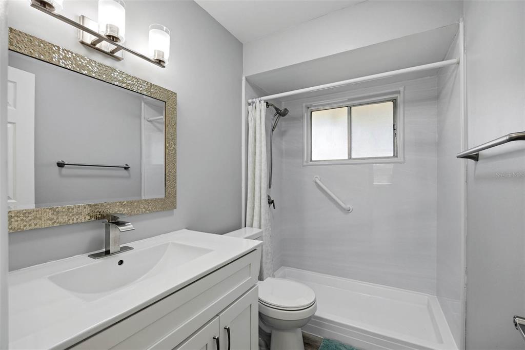 A bathroom features a white vanity, a mirror with a textured frame, and a shower-tub — 2900 45TH STREET S UNIT 7, GULFPORT, FL