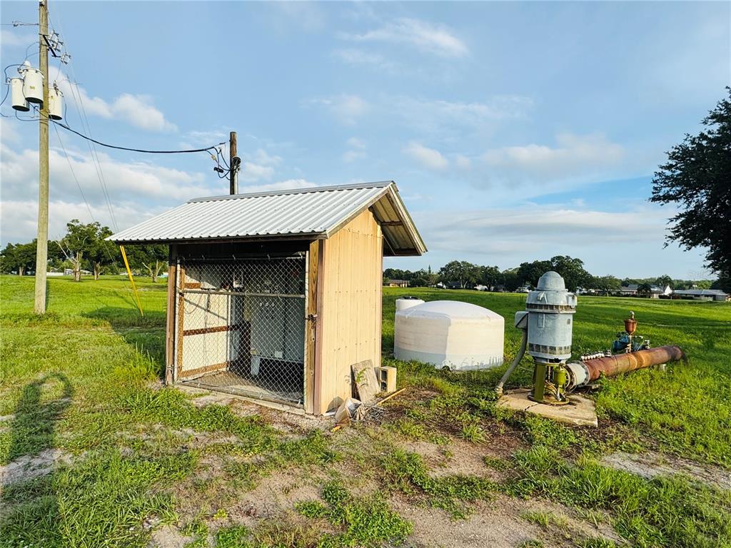A small shed with a metal roof stands next to a water pump and tank — 119 LINCOLN ROAD NW, LAKE PLACID, FL