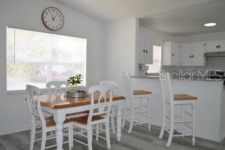 A dining area with a wooden table and white chairs sits adjacent to a kitchen counter — 6516 E 25TH AVENUE, TAMPA, FL