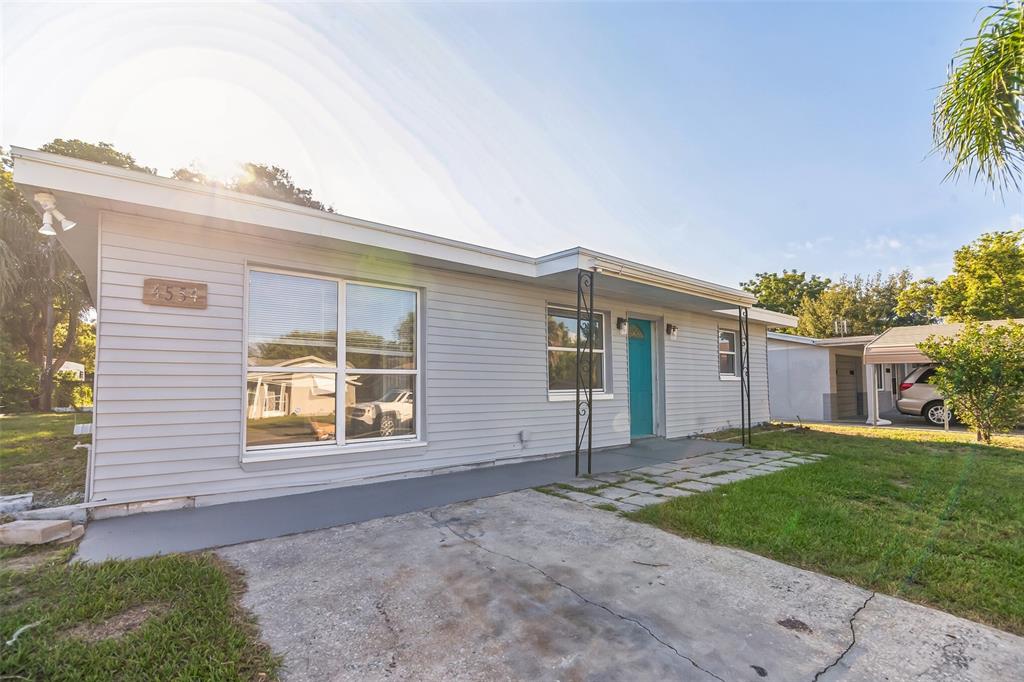 A single-story gray house with a teal front door and a concrete driveway — 4554 NIMMER DRIVE, NEW PORT RICHEY, FL