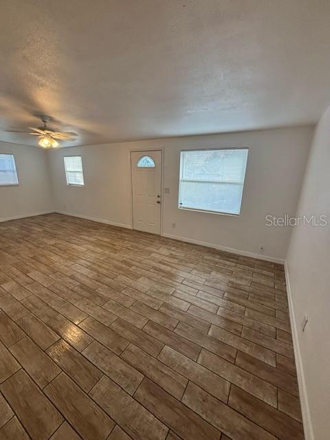 An empty room features light-colored walls, a ceiling fan, and wood-look tile flooring — 4554 NIMMER DRIVE, NEW PORT RICHEY, FL