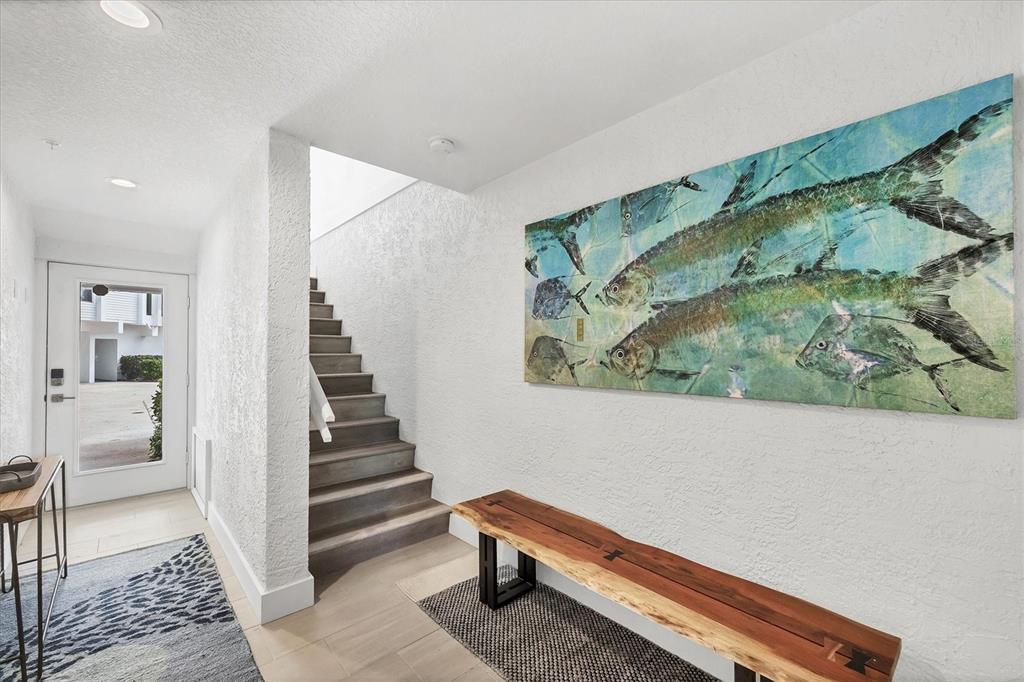 An entryway features a wooden bench, a large fish painting, and stairs leading upward — 8234 HARBORSIDE CIRCLE, ENGLEWOOD, FL