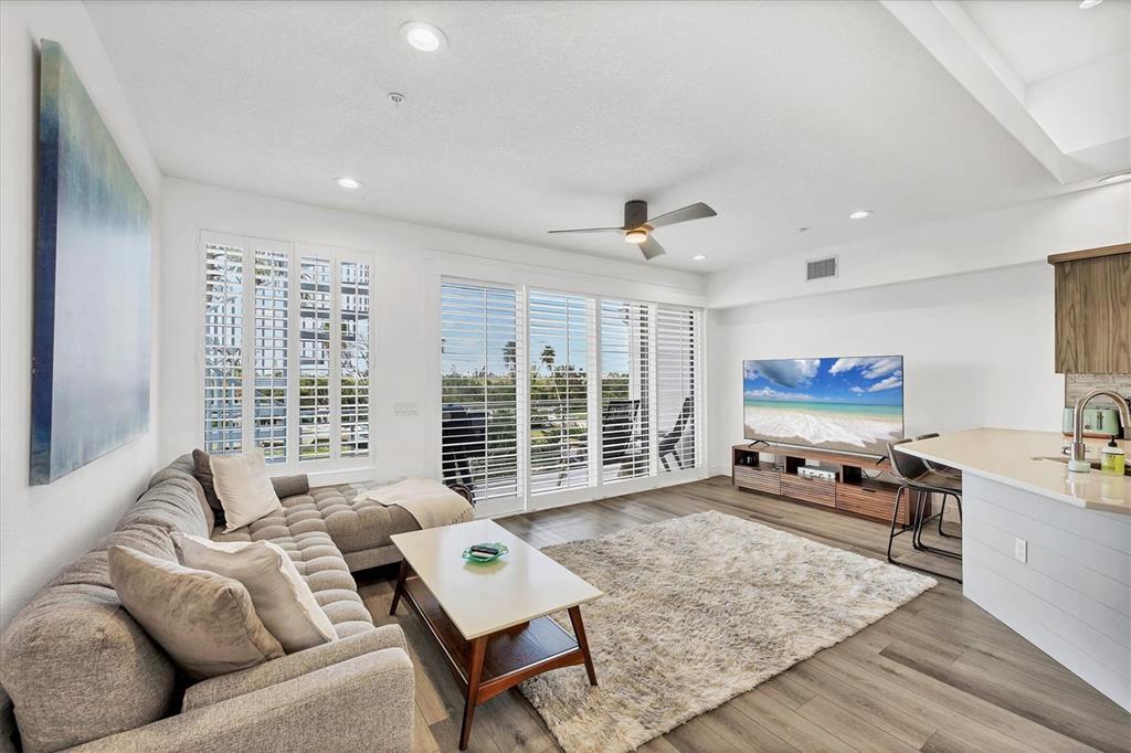 A living room features a gray sectional sofa, a coffee table, and a large television — 8234 HARBORSIDE CIRCLE, ENGLEWOOD, FL