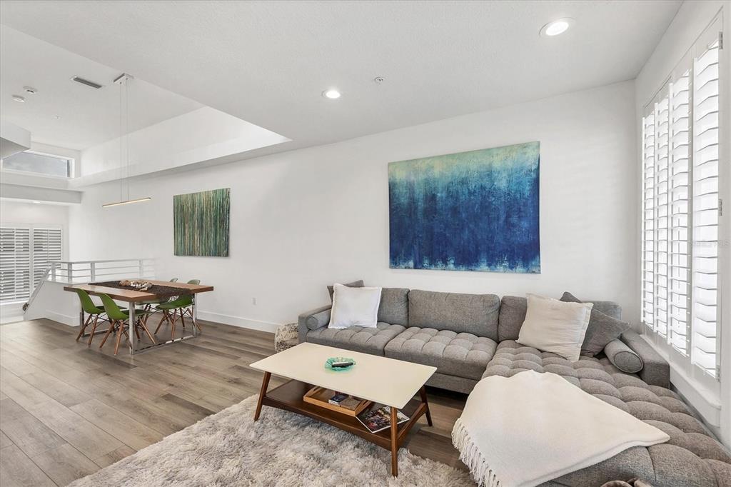 A living room with a grey sectional sofa, coffee table, and dining area with green chairs — 8234 HARBORSIDE CIRCLE, ENGLEWOOD, FL