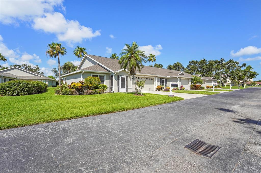 A single-story duplex with a gray roof, beige siding, and a manicured lawn — 2417 FAIRWAY OAKS DRIVE UNIT 22, PALMETTO, FL