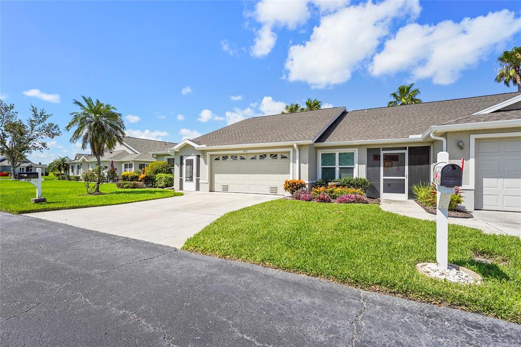 A single-story house with a beige exterior, a two-car garage, and a manicured front lawn — 2417 FAIRWAY OAKS DRIVE UNIT 22, PALMETTO, FL