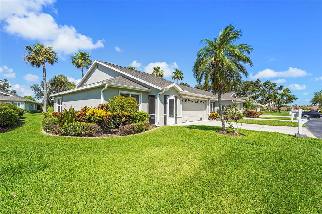 A single-story house with a beige exterior, a two-car garage, and palm trees in Florida — 2417 FAIRWAY OAKS DRIVE UNIT 22, PALMETTO, FL