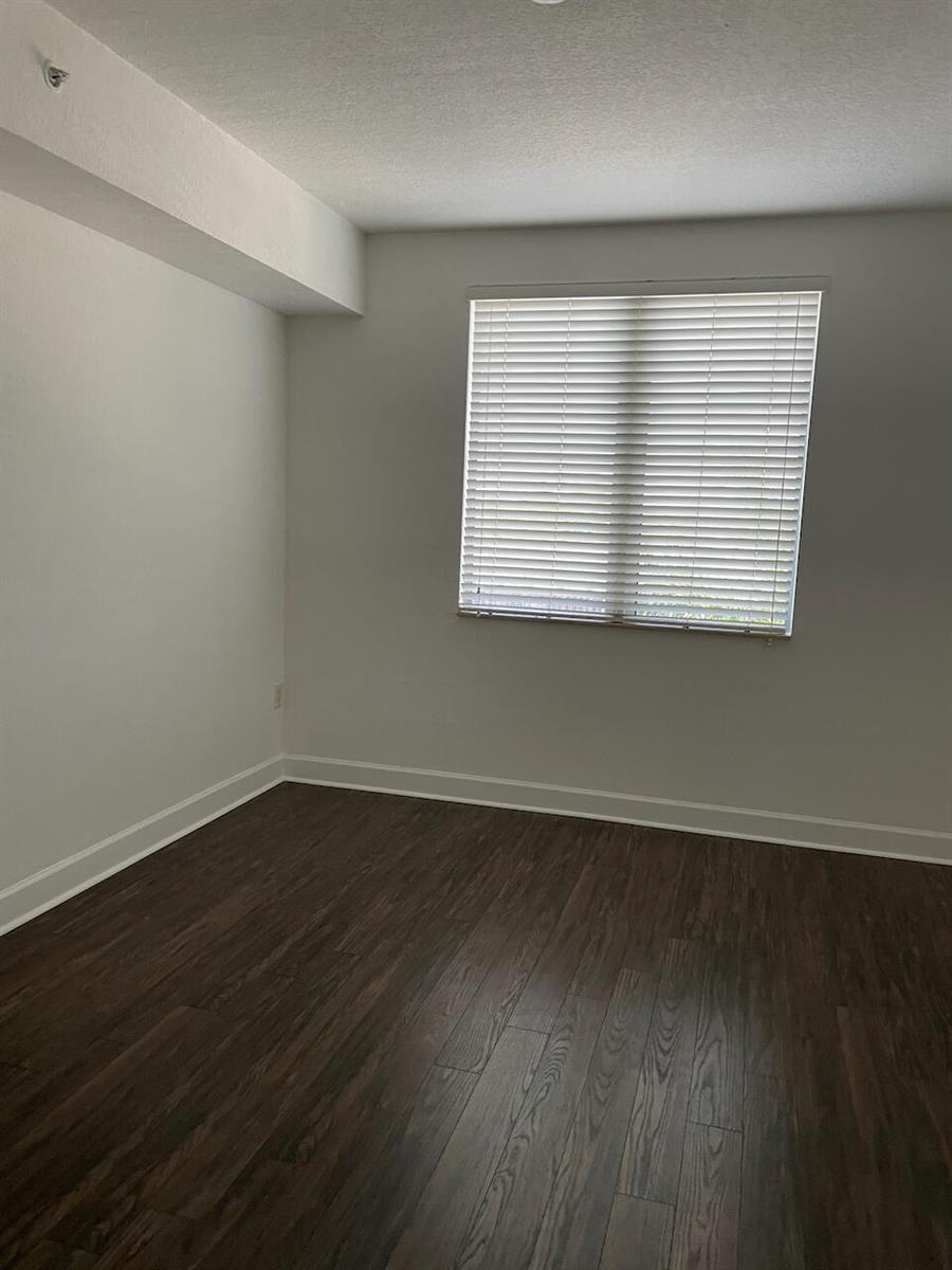 An empty room with white walls, a window with blinds, and dark wood-look flooring — 1830 Radius Drive # 307, Hollywood FL 33020, HOLLYWOOD, FL