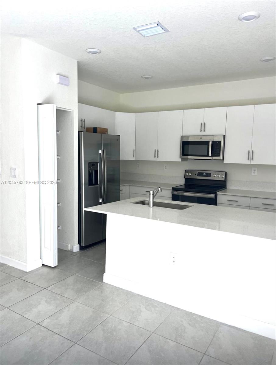 A kitchen features white cabinets, stainless steel appliances, a center island, and tiled flooring — 11444 W 33rd Ct # 0, Hialeah FL 33018, HIALEAH, FL