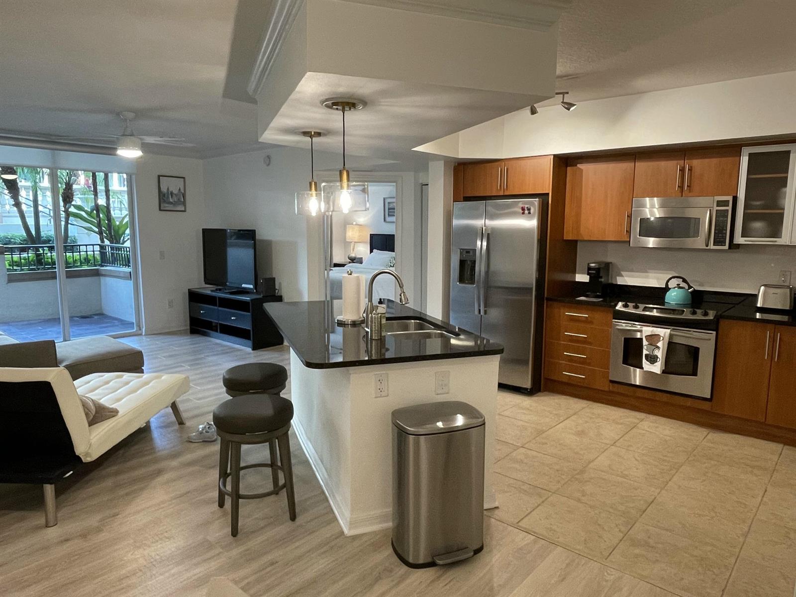 A kitchen with wood cabinets and stainless steel appliances opens to a living area — 600 S Dixie Highway # 534, West Palm Beach FL 33401, WEST PALM BEACH, FL