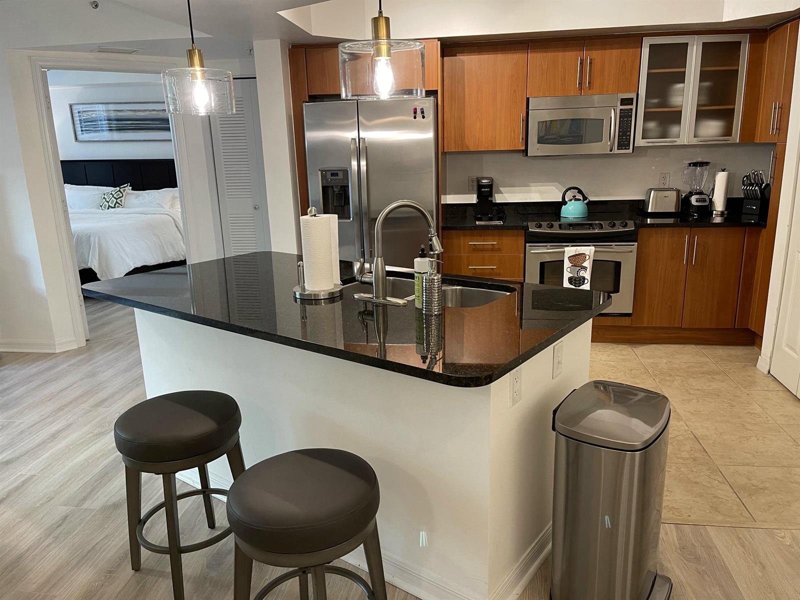 A kitchen with dark granite countertops, wood cabinets, stainless steel appliances, and a breakfast bar — 600 S Dixie Highway # 534, West Palm Beach FL 33401, WEST PALM BEACH, FL