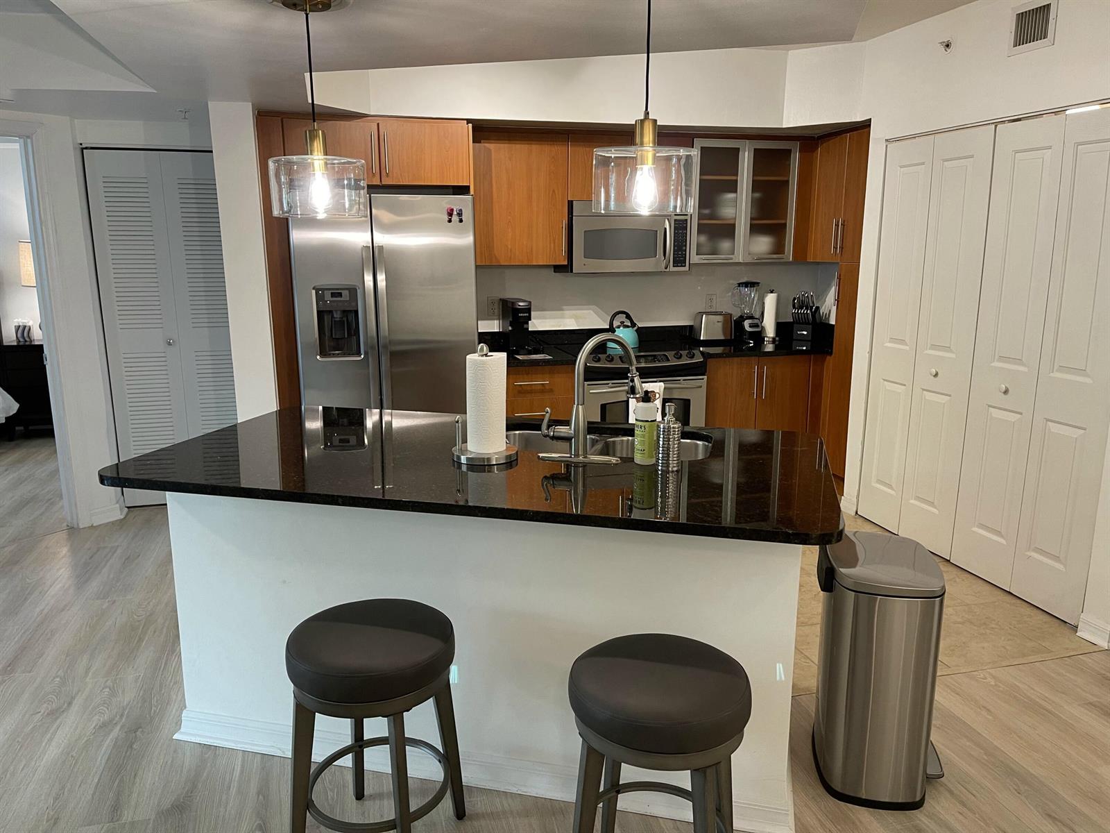 A kitchen features wood cabinets, stainless steel appliances, a black granite island, and two stools — 600 S Dixie Highway # 534, West Palm Beach FL 33401, WEST PALM BEACH, FL
