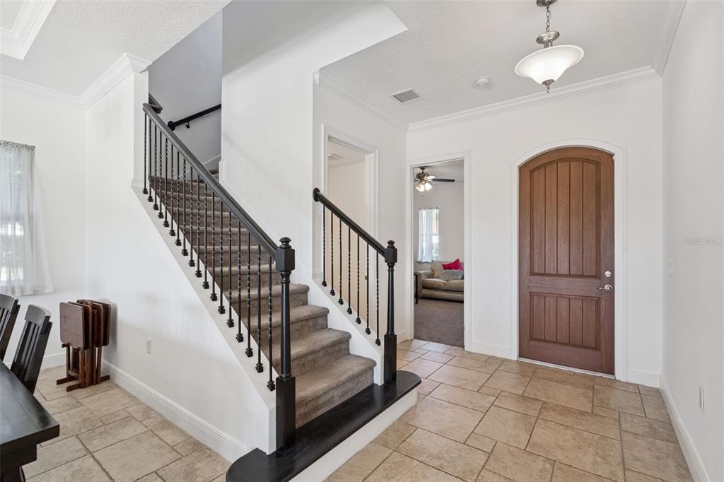 An entryway features a carpeted staircase with black railings, tile flooring, and a wooden door — 15672 SHOREBIRD LANE, WINTER GARDEN, FL