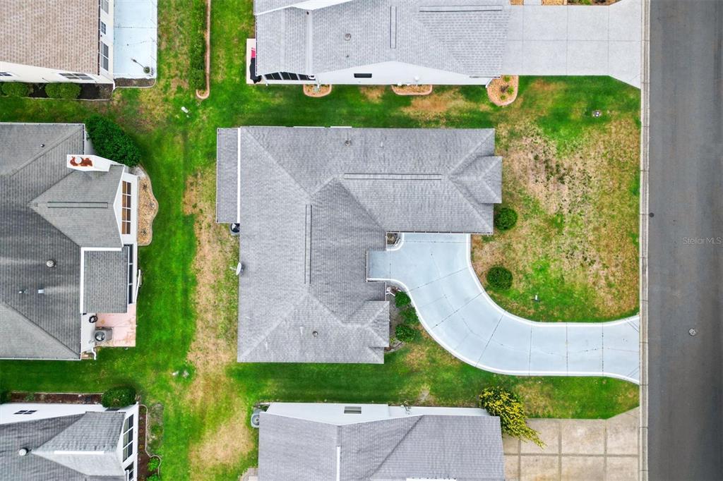 An aerial view shows a residential house with a gray roof and a curved driveway — 1008 VENTURA DRIVE, LADY LAKE, FL