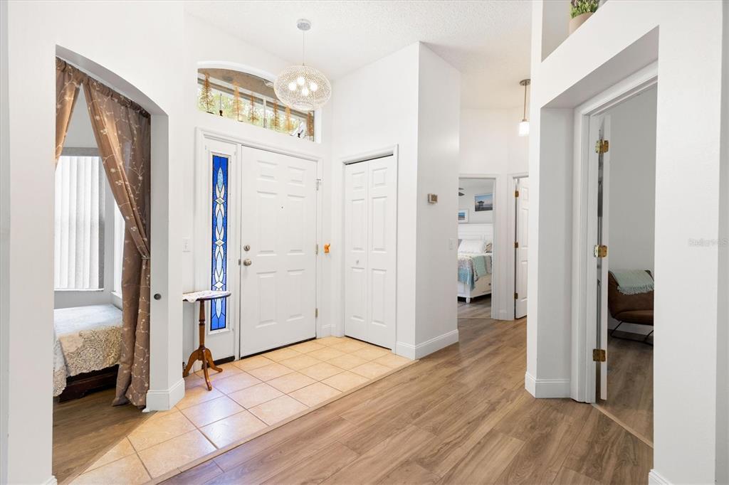 An entryway with tile flooring, a white front door, and wood-look laminate flooring beyond — 1008 VENTURA DRIVE, LADY LAKE, FL