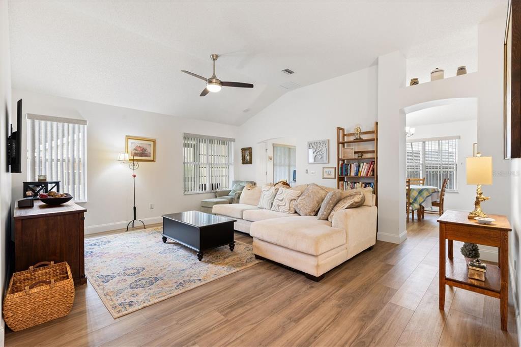A living room with light wood flooring, a sectional sofa, and a vaulted ceiling — 1008 VENTURA DRIVE, LADY LAKE, FL