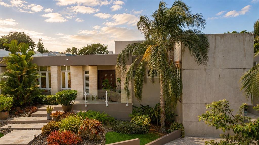 A modern house exterior features a concrete facade, stone accents, and lush tropical landscaping — A31 INGENIERO ROBERTO ARANA STREET, GUAYNABO, PR