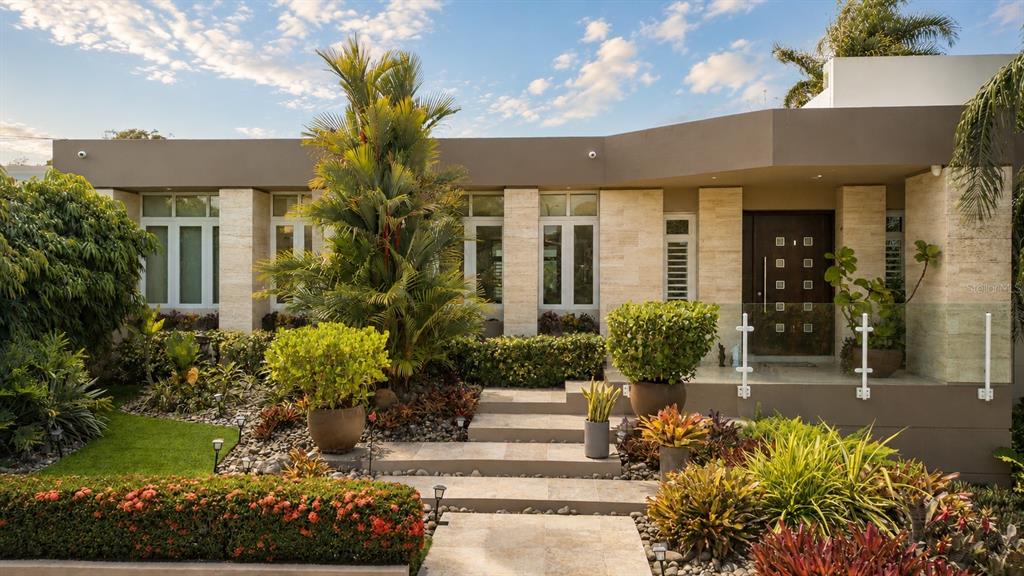 A modern house exterior features stone cladding, a glass-railed porch, and lush tropical landscaping — A31 INGENIERO ROBERTO ARANA STREET, GUAYNABO, PR