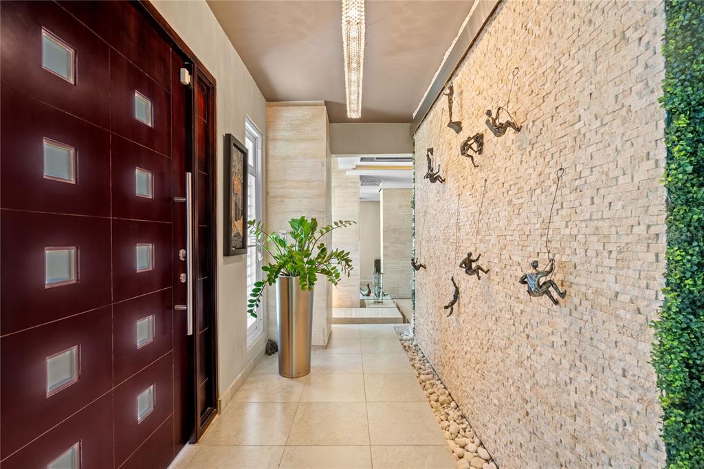 A modern entryway features a dark wood door, stone accent wall with climber sculptures, and tile — A31 INGENIERO ROBERTO ARANA STREET, GUAYNABO, PR