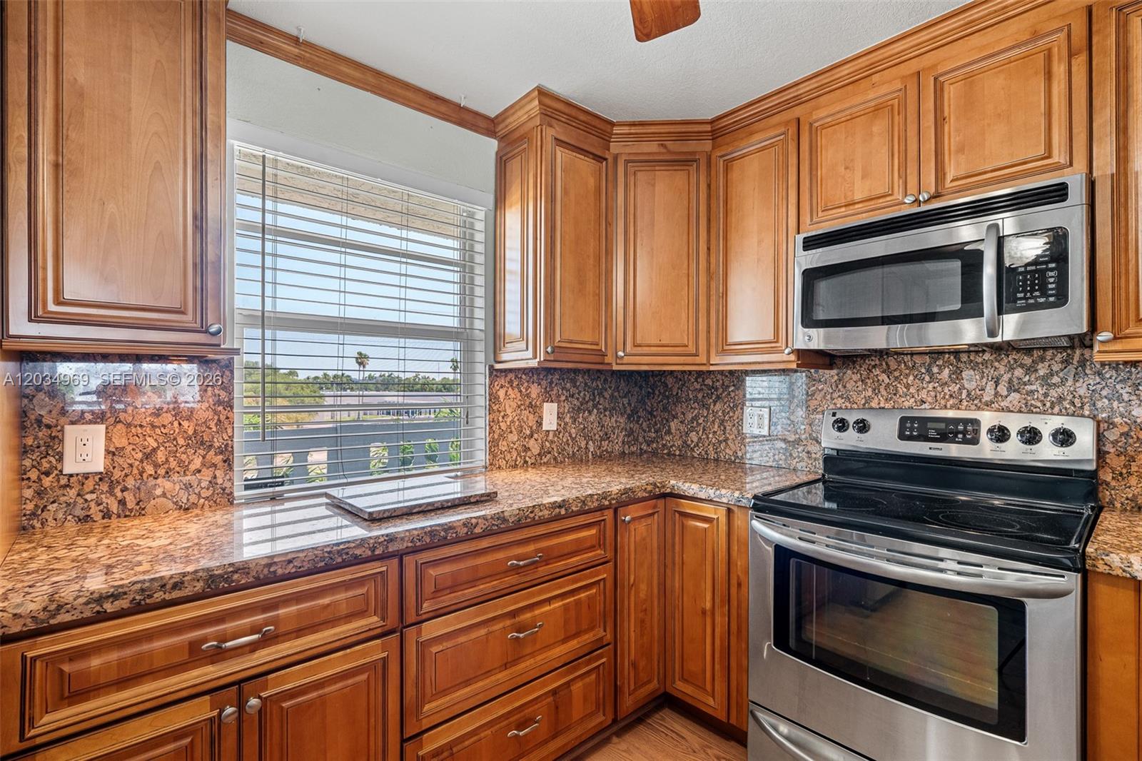 A kitchen features wood cabinets, granite countertops, stainless steel appliances, and a window with blinds — 325 SE 11th Ter # 308, Dania Beach FL 33004, DANIA BEACH, FL