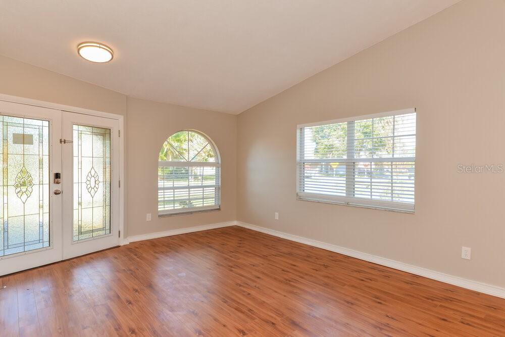 An empty room with wood-look flooring, a glass-paneled door, and an arched window — 12914 ASTORWOOD PLACE, RIVERVIEW, FL