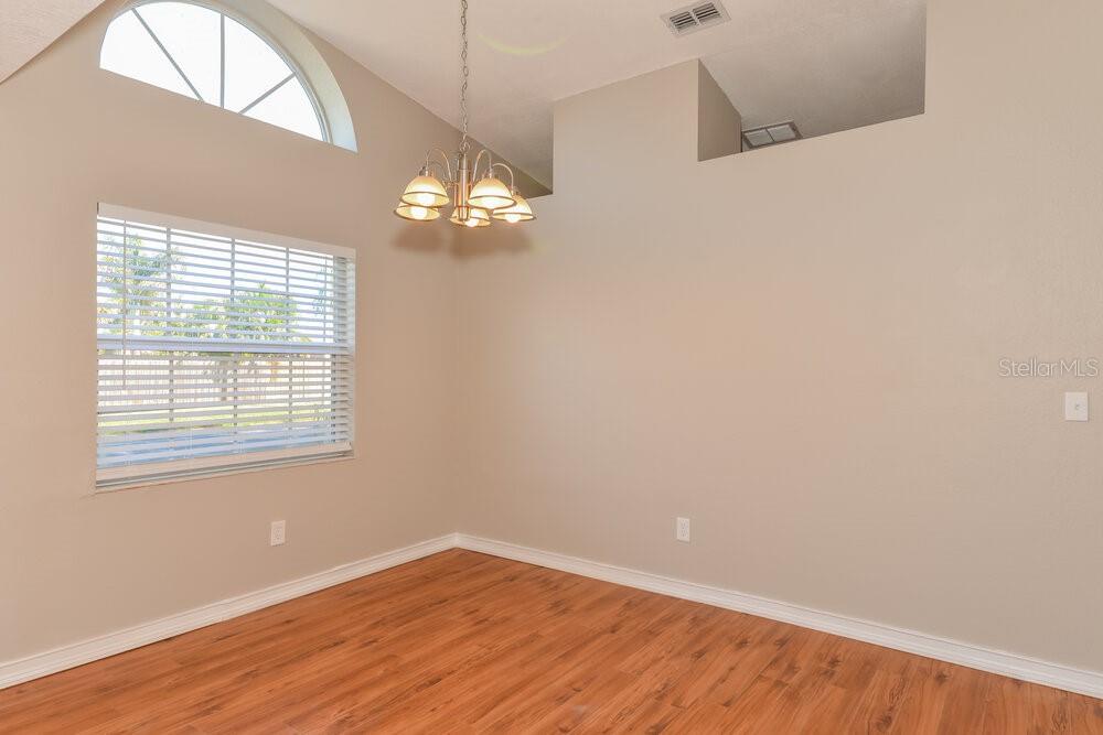 A dining room with wood-look flooring, a vaulted ceiling, and a multi-light chandelier — 12914 ASTORWOOD PLACE, RIVERVIEW, FL