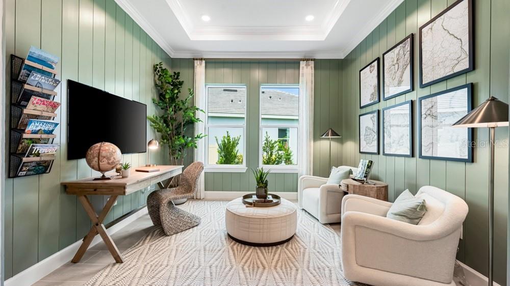 A home office features green vertical-plank walls, a wooden desk, two armchairs, and a central ottoman — 26120 ASPARANO AVENUE, ENGLEWOOD, FL