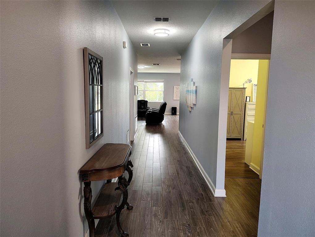 A hallway with wood-look tile flooring leads to a living area with a window — 1047 OAK BLUFF DRIVE, DAVENPORT, FL
