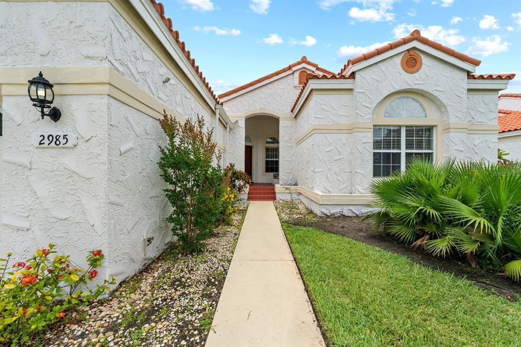A concrete walkway leads to the front entrance of a white stucco house with tile — 2985 LA CONCHA DRIVE, CLEARWATER, FL