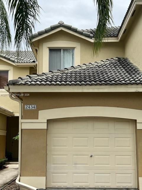A tan two-story house features a tiled roof, a garage, and a second-story window — 2434 Cordoba Bnd # 2434, Weston FL 33327, WESTON, FL