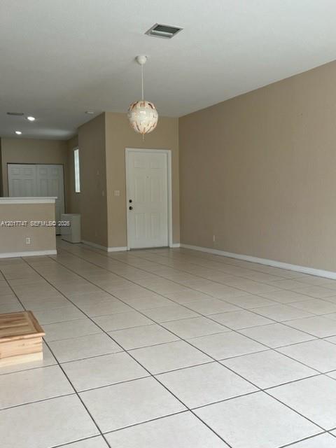 An empty room features light-colored tile flooring, beige walls, and a hanging pendant light — 2434 Cordoba Bnd # 2434, Weston FL 33327, WESTON, FL