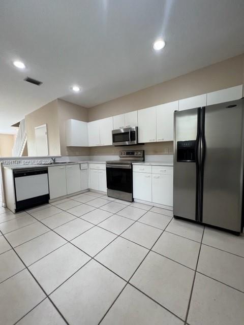A kitchen features white cabinets, stainless steel appliances, and light-colored tile flooring — 2434 Cordoba Bnd # 2434, Weston FL 33327, WESTON, FL