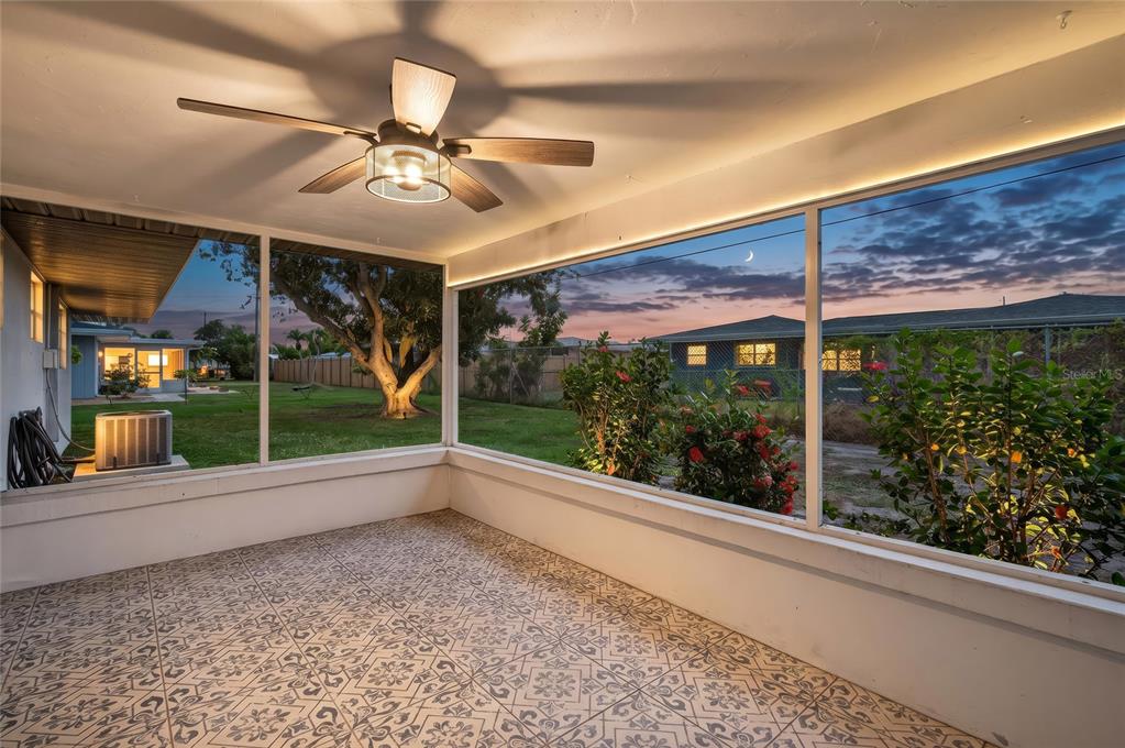 A screened-in porch with patterned tile flooring, a ceiling fan, and views of a backyard — 337 COLGAN AVENUE SE, PORT CHARLOTTE, FL