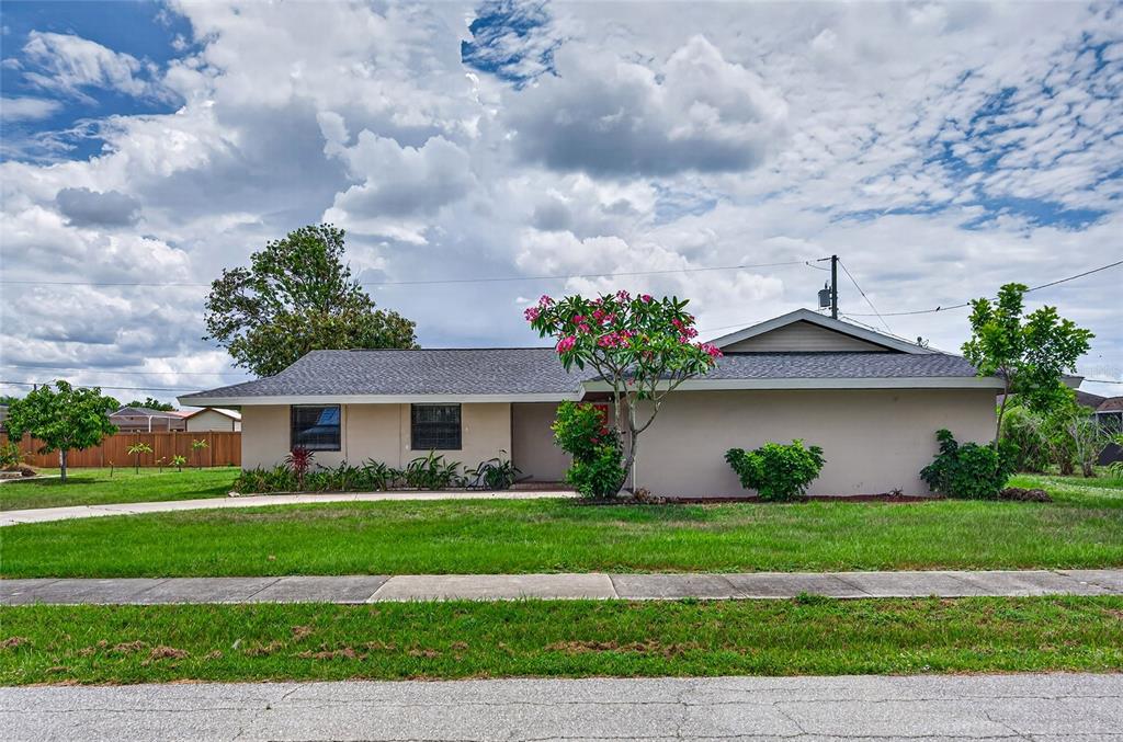 A single-story house with a beige exterior, dark roof, and a flowering tree in front — 337 COLGAN AVENUE SE, PORT CHARLOTTE, FL