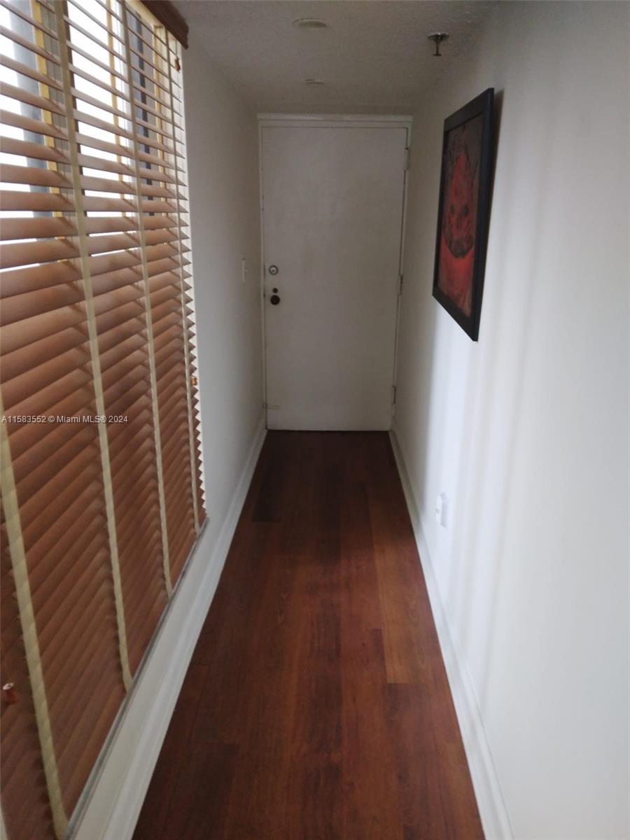 A narrow hallway features dark wood flooring, white walls, and a window with wooden blinds — 911 Ponce De Leon Blvd # 904, Coral Gables FL 33134, CORAL GABLES, FL