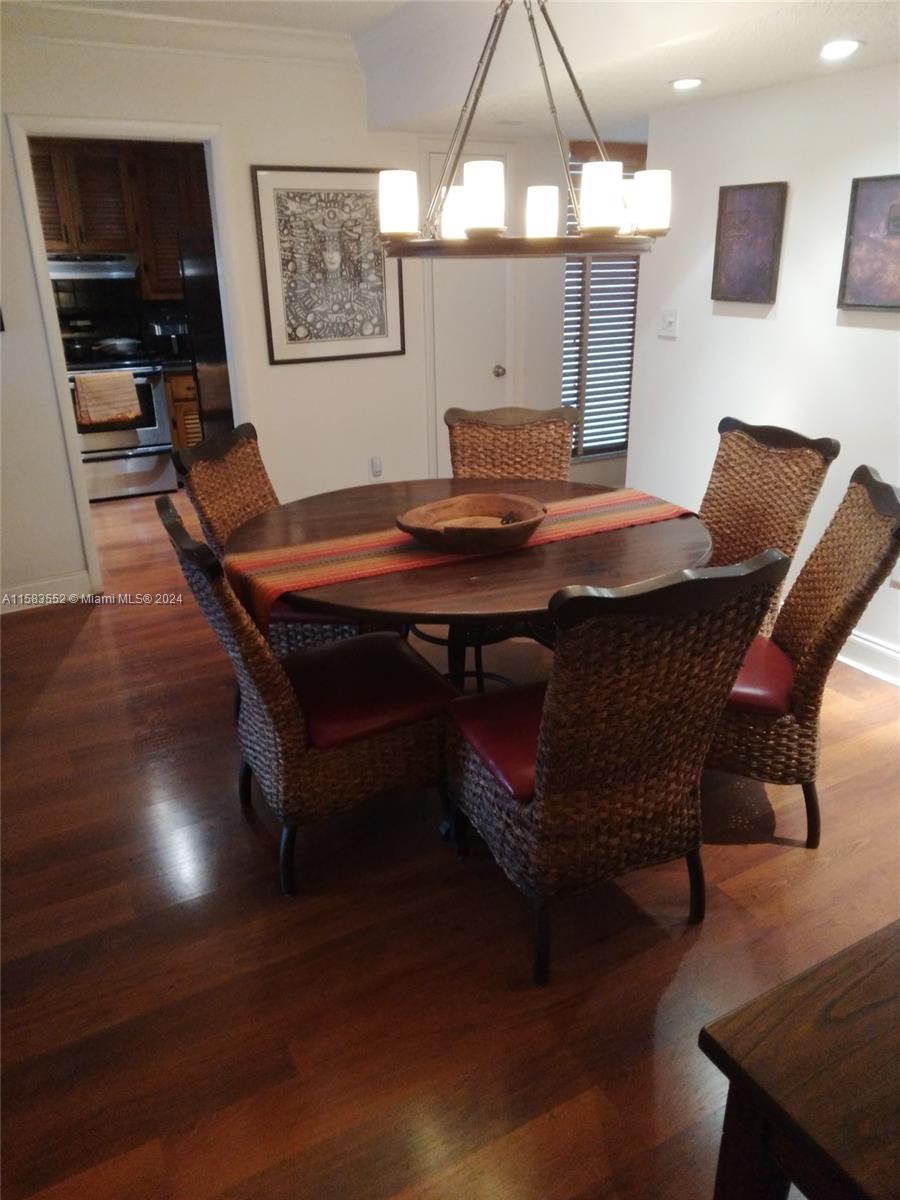 A dining room features a round wooden table, wicker chairs, and a hanging light fixture — 911 Ponce De Leon Blvd # 904, Coral Gables FL 33134, CORAL GABLES, FL