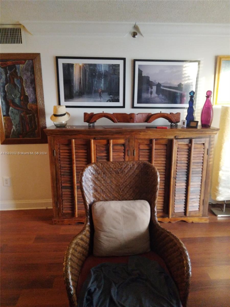 A wicker chair sits in front of a wooden shuttered cabinet topped with framed artwork — 911 Ponce De Leon Blvd # 904, Coral Gables FL 33134, CORAL GABLES, FL