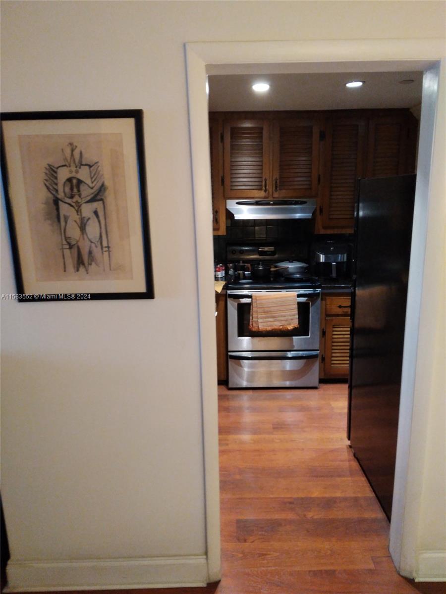 A view through a doorway into a kitchen with wood cabinets and stainless steel appliances — 911 Ponce De Leon Blvd # 904, Coral Gables FL 33134, CORAL GABLES, FL