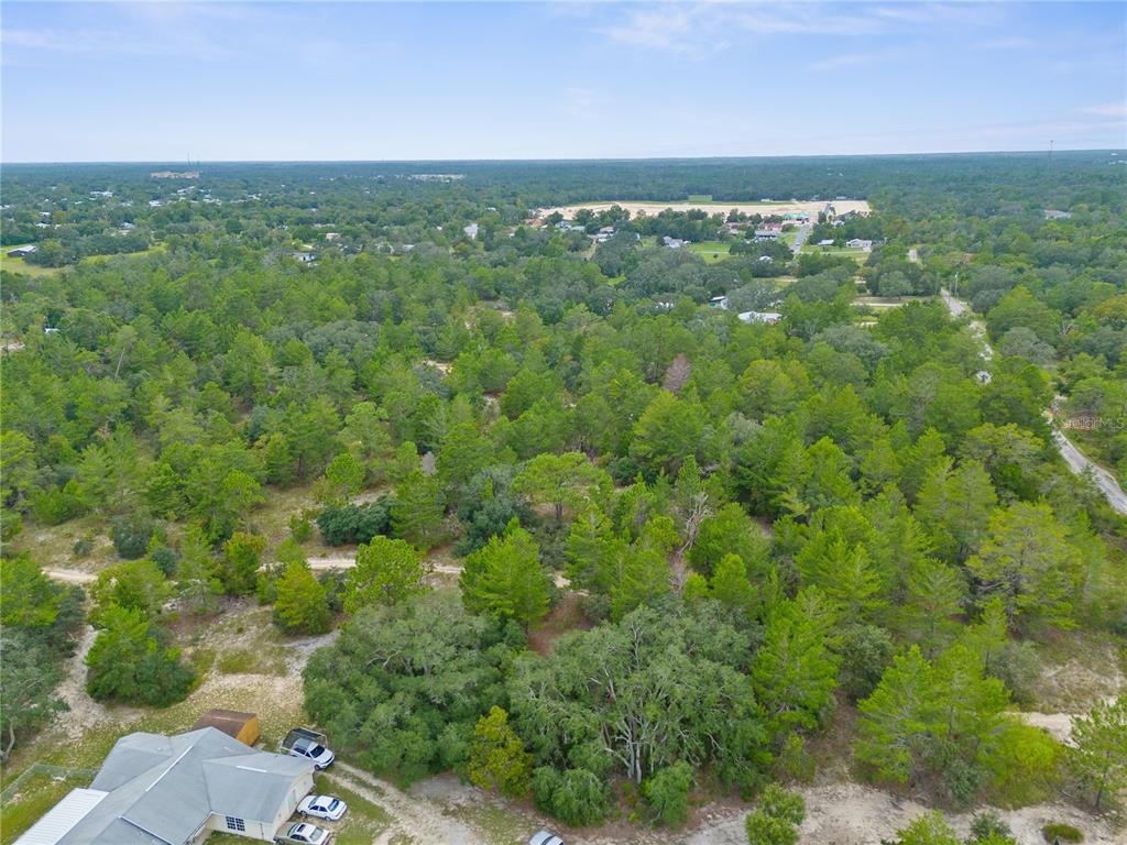 An aerial view shows a house with a driveway surrounded by a large, wooded lot — MADISON STREET, BROOKSVILLE, FL