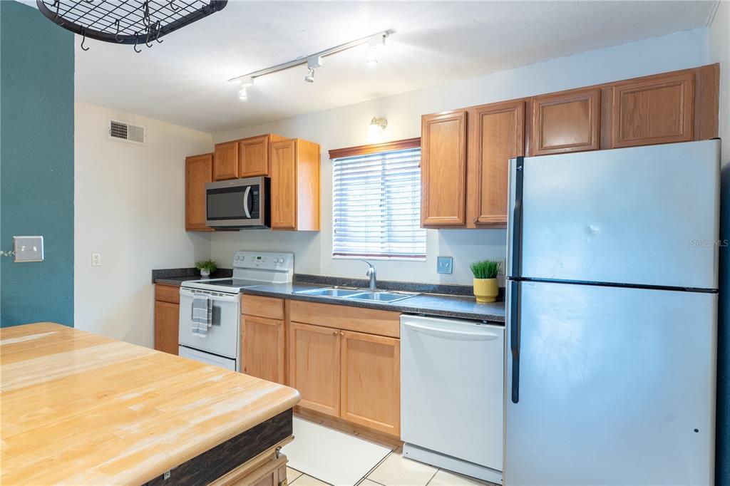 A kitchen features wood cabinets, stainless steel appliances, a center island, and wood-look flooring — 507 NW 39TH ROAD UNIT 132, GAINESVILLE, FL