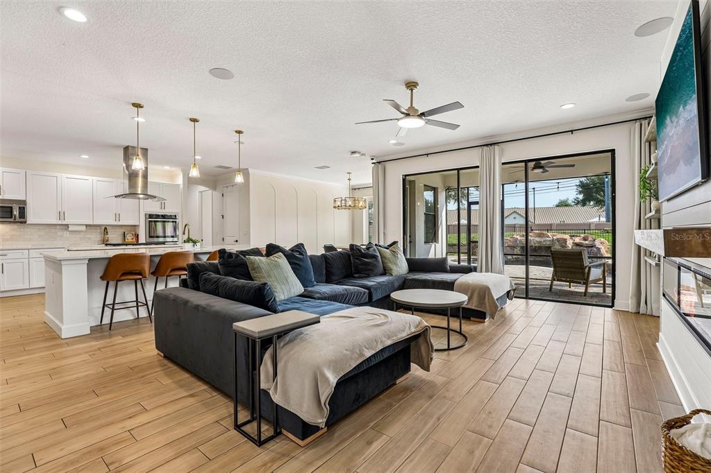 A modern open-concept living room and kitchen featuring a large sectional sofa and tile floors — 5785 SAYBROOK CIRCLE, SANFORD, FL