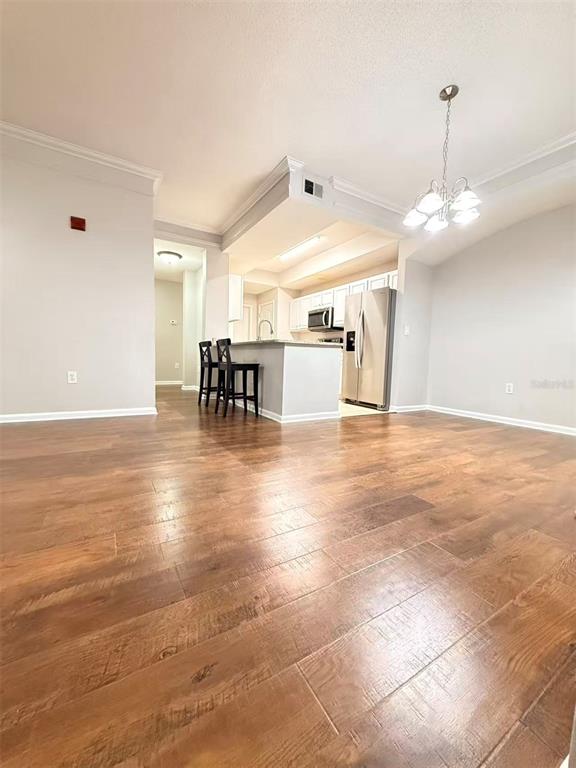 A kitchen with white cabinets and stainless steel appliances overlooks a dining area with wood flooring — 12017 VILLANOVA DRIVE UNIT 109, ORLANDO, FL