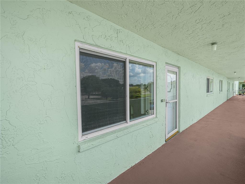 An exterior view of a building with a light green stucco wall and a walkway — 1130 N LAKE PARKER AVENUE UNIT A308, LAKELAND, FL
