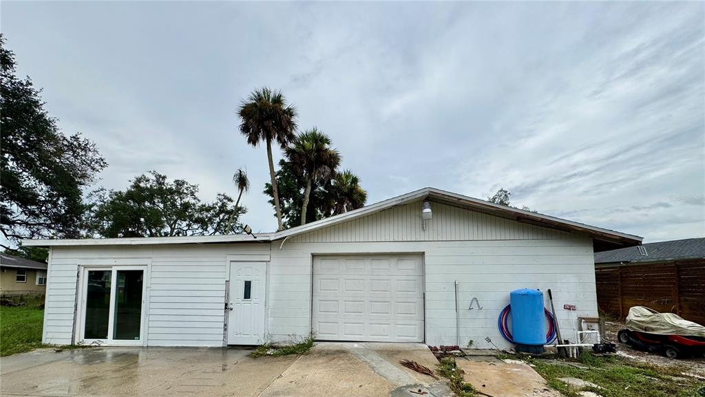 A white detached garage with a sliding glass door, a side door, and a driveway — 812 TROPICAL DRIVE, BRADENTON, FL