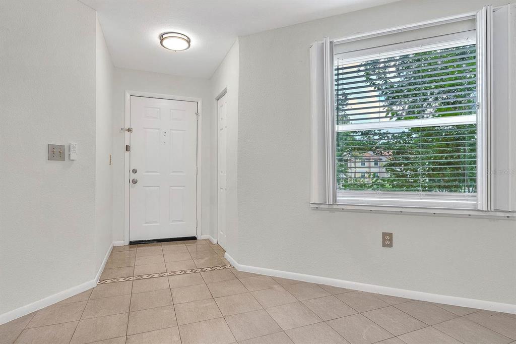 An entryway with light-colored tile flooring, a white front door, and a large window — 3032 PARKWAY BOULEVARD UNIT 201, KISSIMMEE, FL