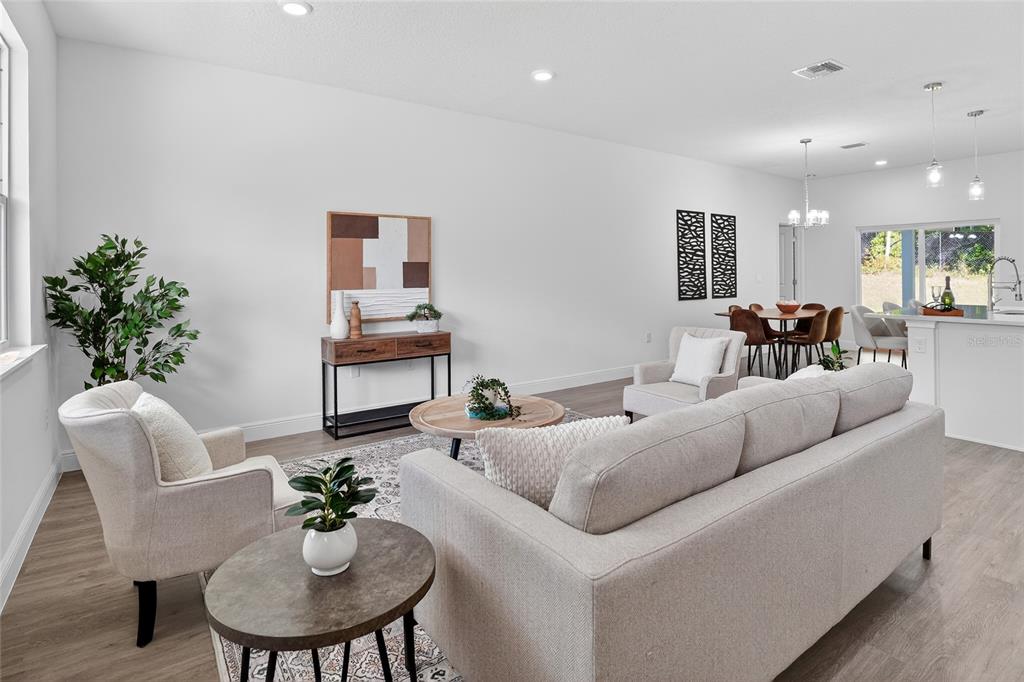 A living room with a sofa, armchairs, and a dining area in an open floor plan — 99 W GOLDCOAST PLACE, DUNNELLON, FL