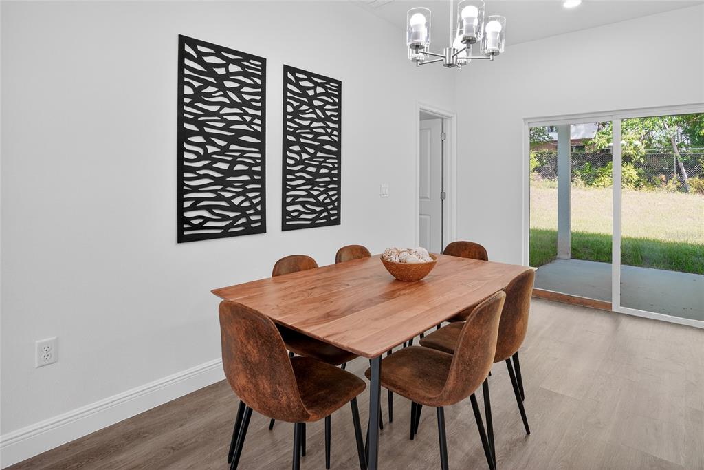 A dining room features a wooden table, six brown chairs, wall art, and a sliding door — 99 W GOLDCOAST PLACE, DUNNELLON, FL
